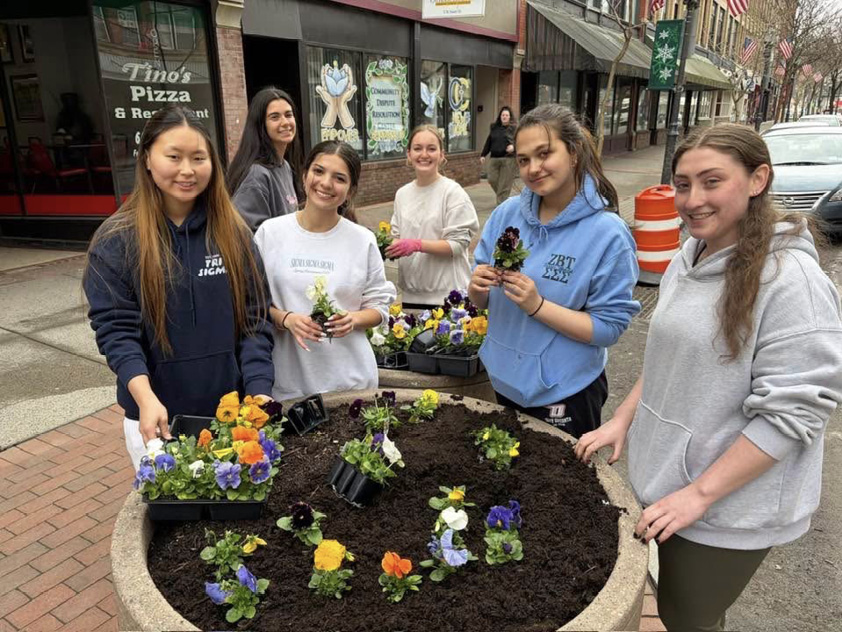Six community members planting flowers in a downtown planter